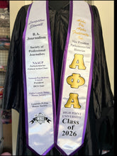 Load image into Gallery viewer, A black graduation gown with two white and purple sashes. The left sash reads 'Langston Stewart B.

