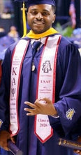 Load image into Gallery viewer, A graduate wearing a navy blue cap and gown with a yellow stole and a white sash featuring the letters 'KAΨ' and 'USAF Class of 2026'.
